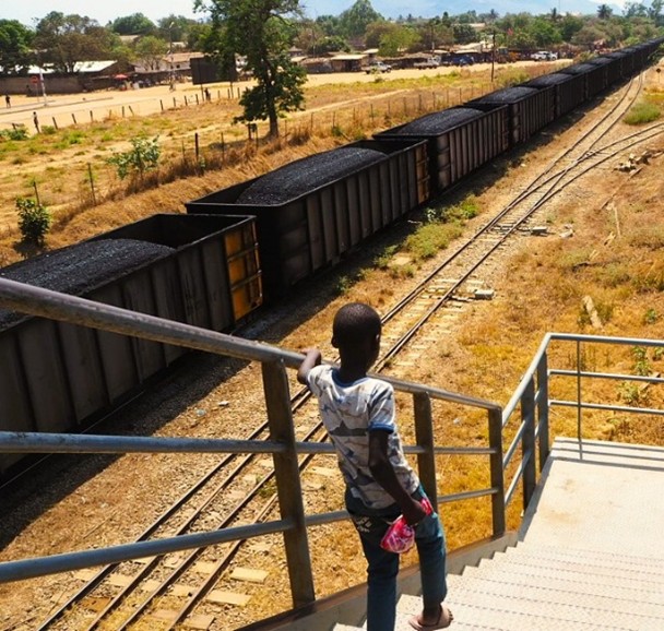 A kid crossing the railway line during the passage of a coal cargo in Cuamba
